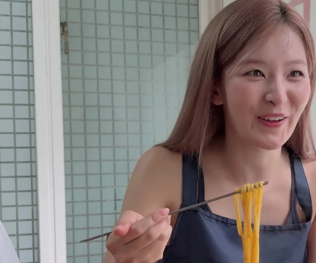 Seulgi smiling while holding noodles at a Haebangchon restaurant — YouTube: Hi Seulgi