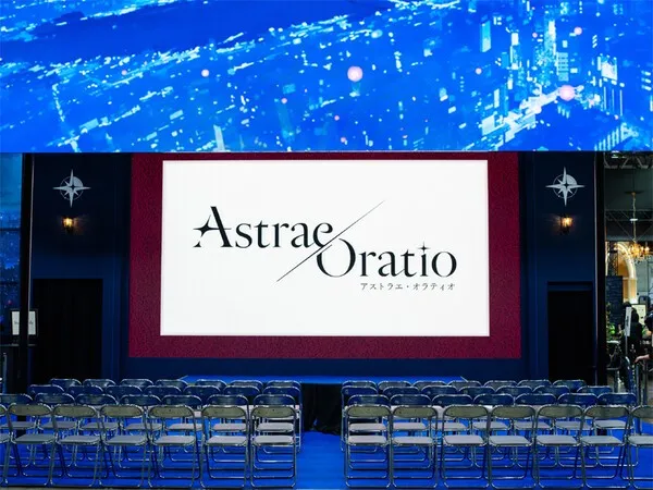 Logo video plays on the central stage of Astrae Oratio as seating areas for attendees and media are prepared.