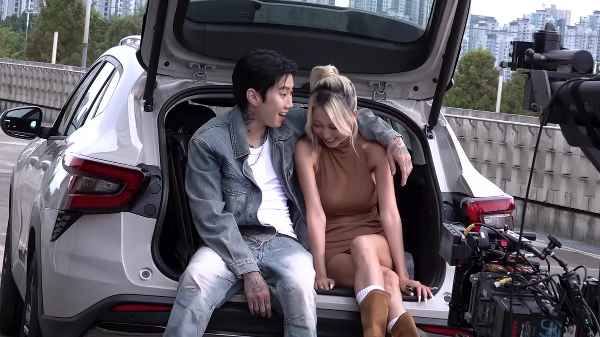Daeyoung y Jay Park posan con una sonrisa afectuosa sentados en el maletero de un coche