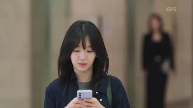 Jeon Hye-won sumida en sus pensamientos mientras mira su teléfono