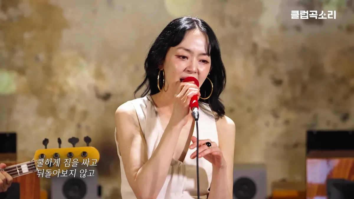 Soyeon performs 'Club Song' while holding a microphone