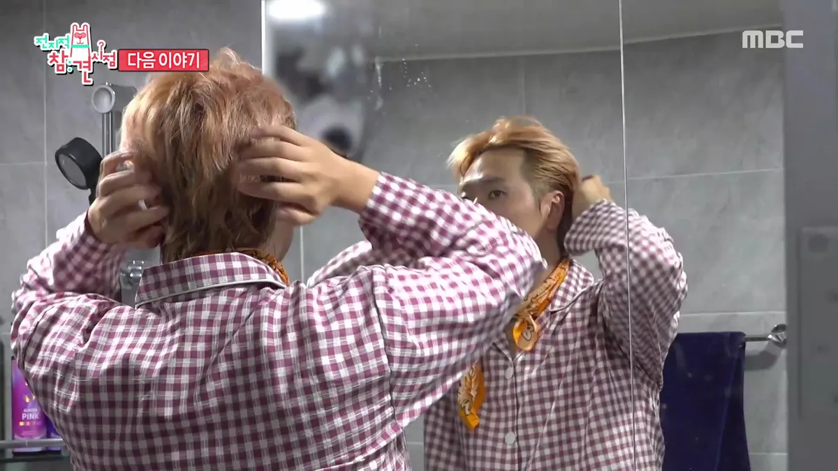 A person grooming their hair while looking in a mirror