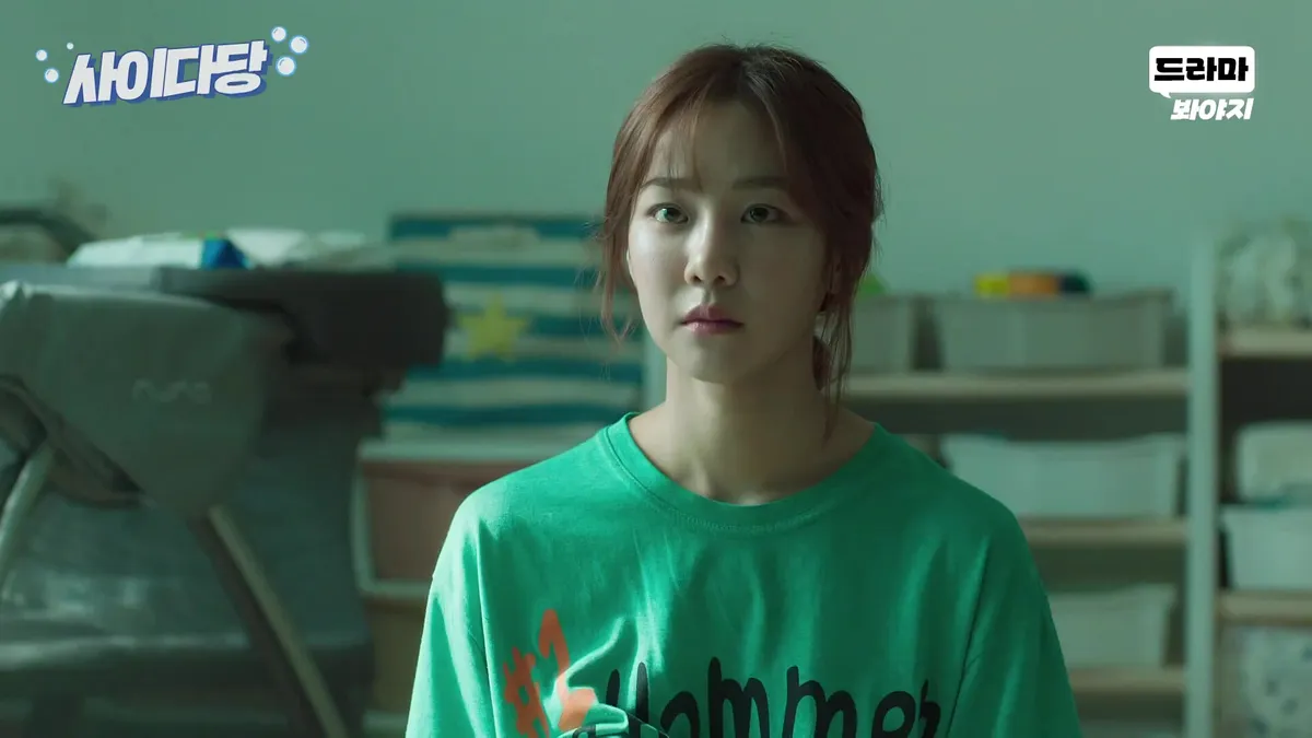 A person wearing a green T-shirt is staring straight ahead.