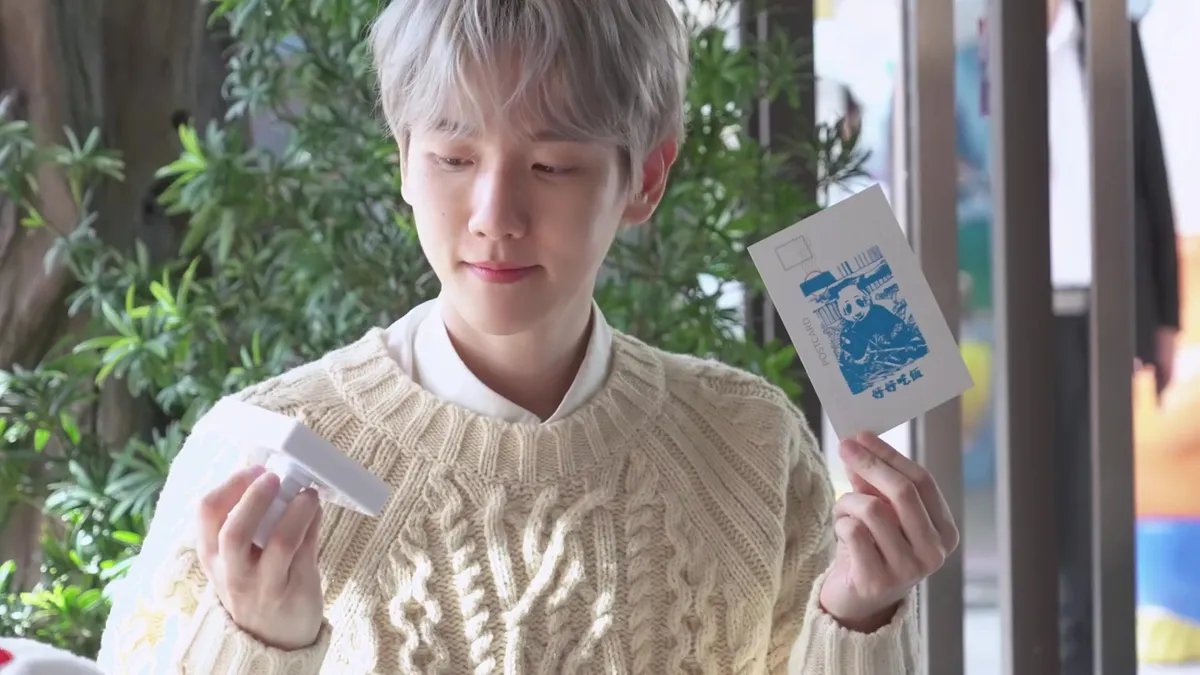 Baekhyun smiling while holding a postcard
