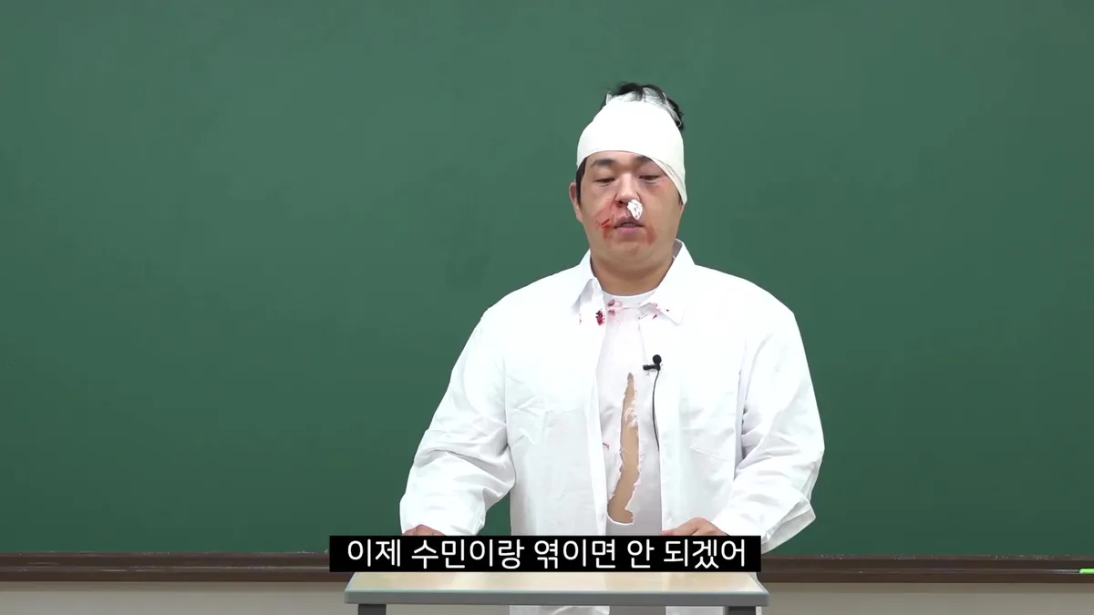 Seo Su-min stands before a chalkboard with bandages on her head and blood on her face