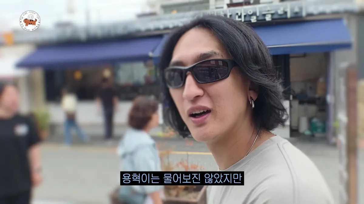 A man wearing sunglasses is talking outdoors.