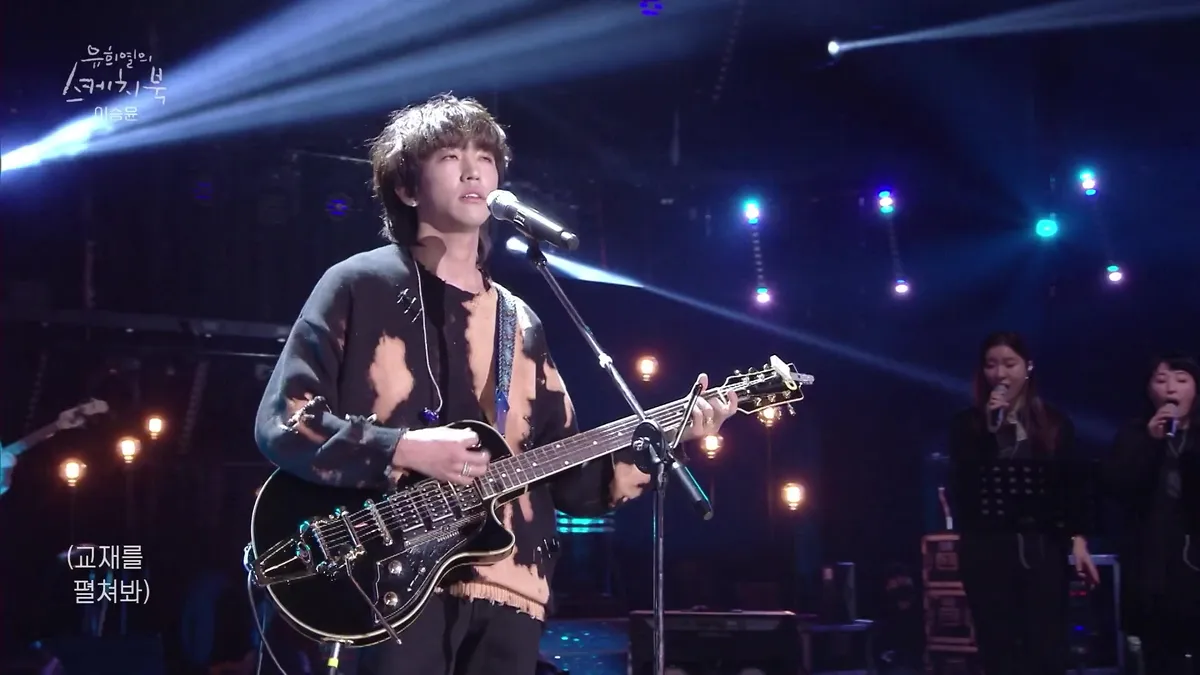 Man singing while playing guitar on stage