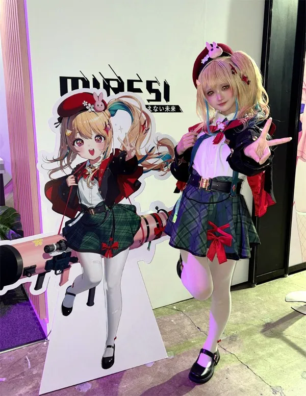 TGS 2026、スマイルゲートのブースで公式モデルのウレハが『未来視』のキャラクター「ニュー」の等身大パネルと共にVサイン