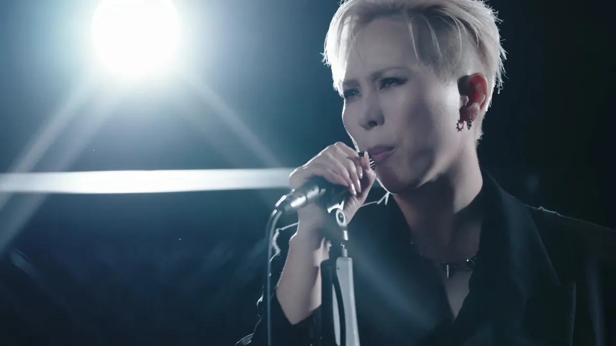 Seo Moon-tak sings while holding a microphone in the 'I Won't Lose' music video