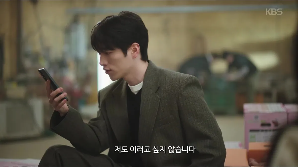 Seo Kang-joon sitting while staring at a smartphone