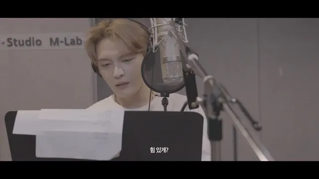 Kim Jae-joong checks lyrics in front of the microphone in THE WAVE recording studio