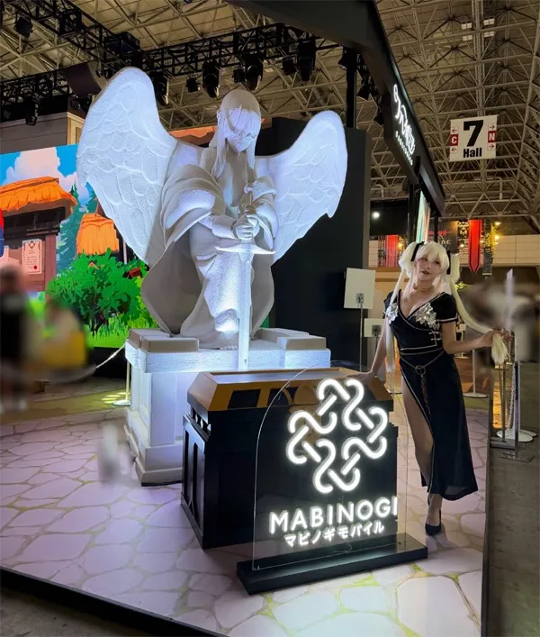 Model Nemu Poses in a Secret Dress in Front of a Giant Goddess Statue at the Mabinogi Mobile Booth