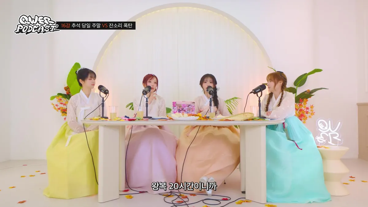 QWER members wearing Hanbok sit around a table and converse