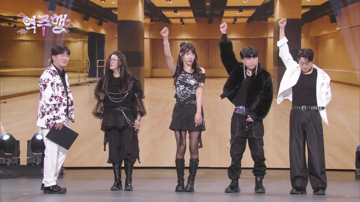 Five performers pose on stage
