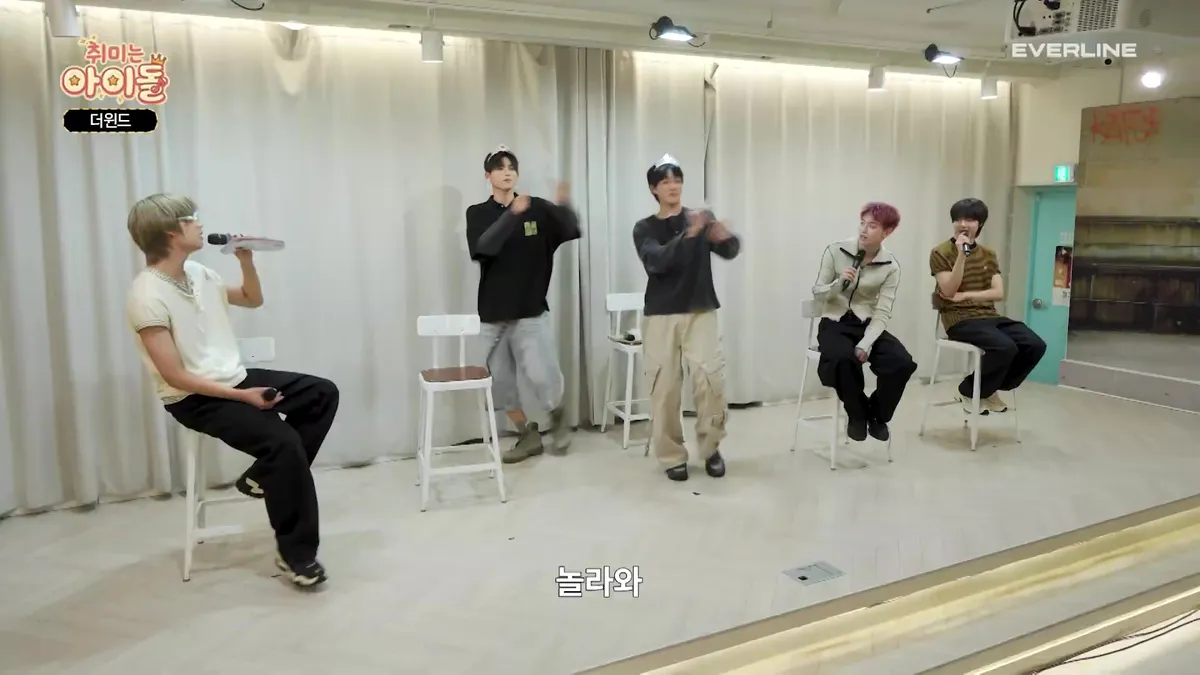 The Wind members enjoying a pleasant conversation while sitting and standing in chairs.